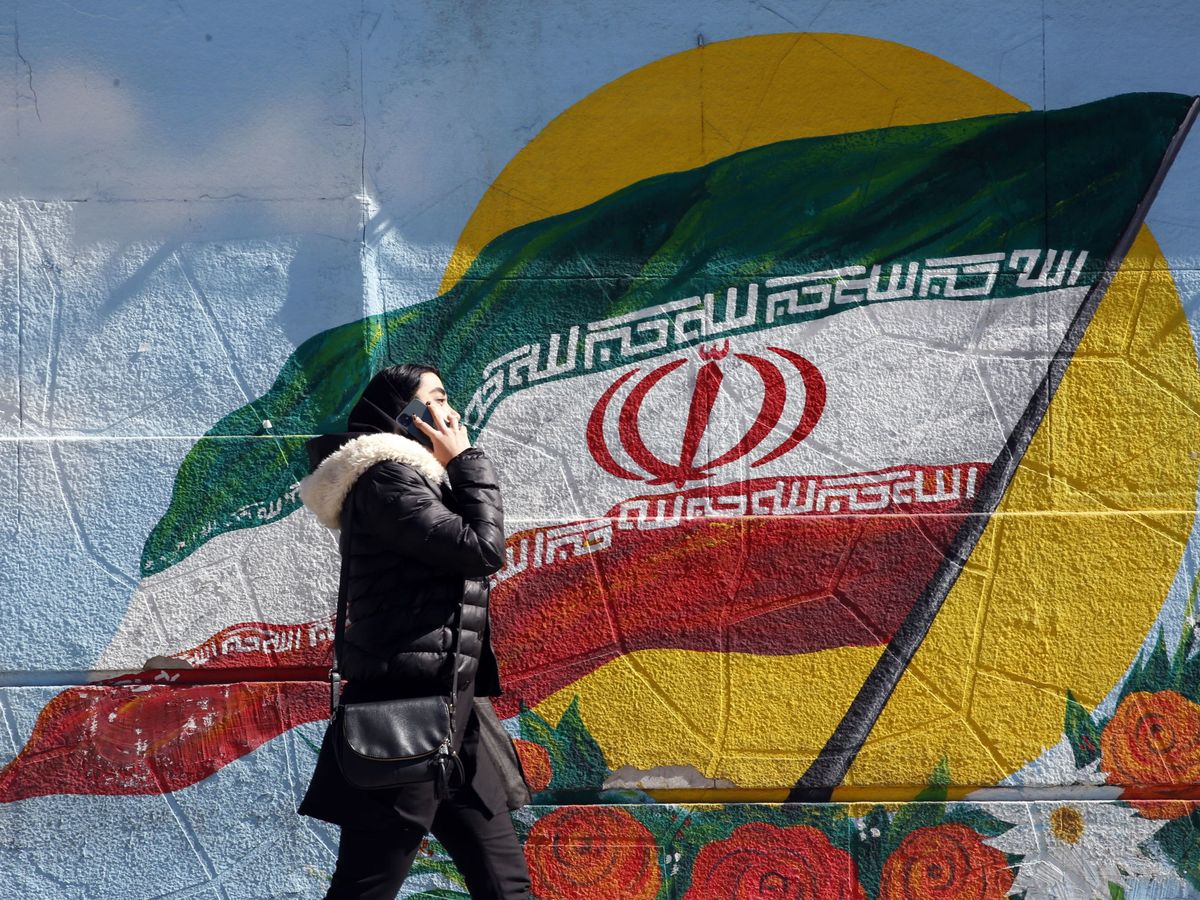 Foto: Una mujer camina frente a un mural de la bandera nacional iraní en Teherán, la capital del país. (Foto: EFE)
