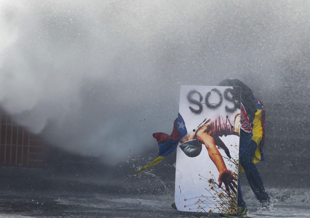 Foto: Un manifestante antichavista se cubre tras un escudo decorado durante una protesta el jueves en Caracas (Reuters).
