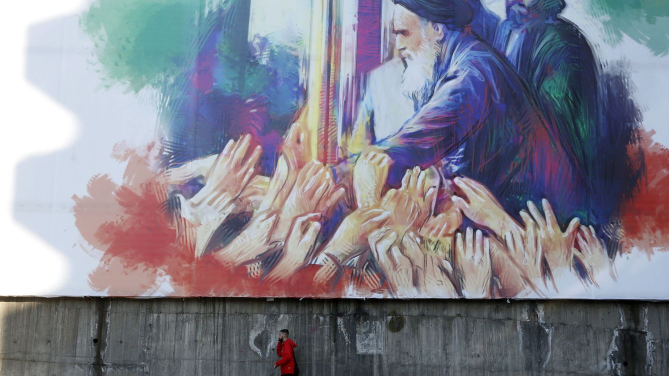 Foto: Un hombre pasa ante un gran mural que muestra al ayatolá Ruholá Jomeiní. (EFE/Abedin Taherkenareh)