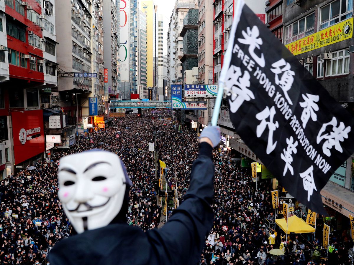 Foto: Un manifestante con una máscara ondea una bandera durante una marcha del Día de los Derechos Humanos. (Reuters)
