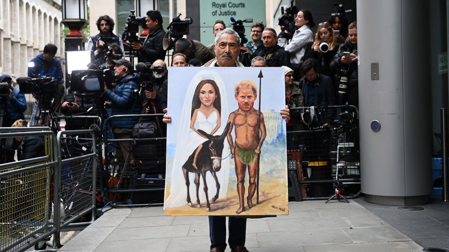 Un hombre sostiene una imagen de los Sussex durante el juicio de Harry en Londres. (Reuters)