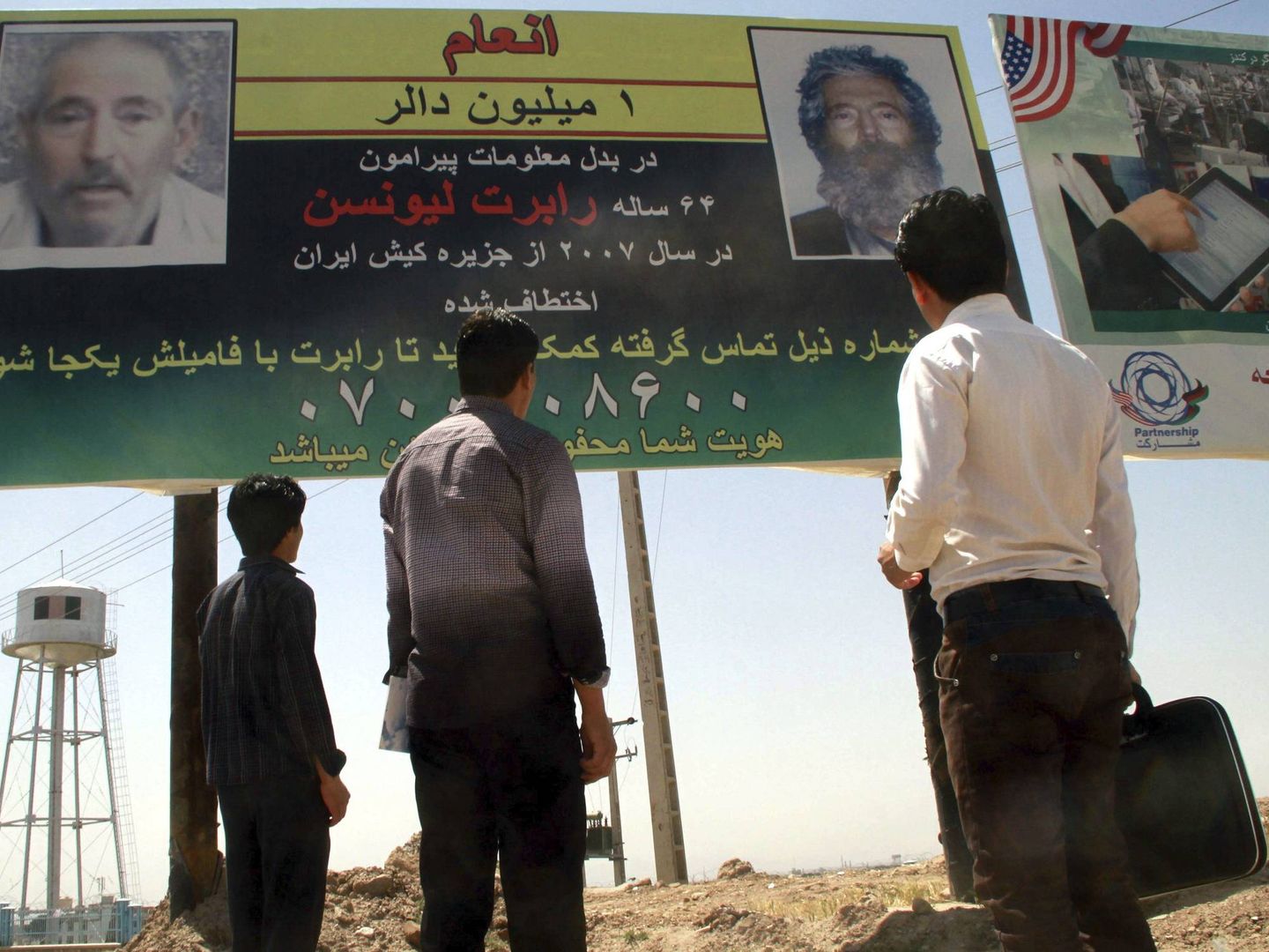 Afganos frente un cartel en el que se anuncia una recompensa de un millón de dólares por cualquier información que pueda ayudar a localizar al agente. (EFE)