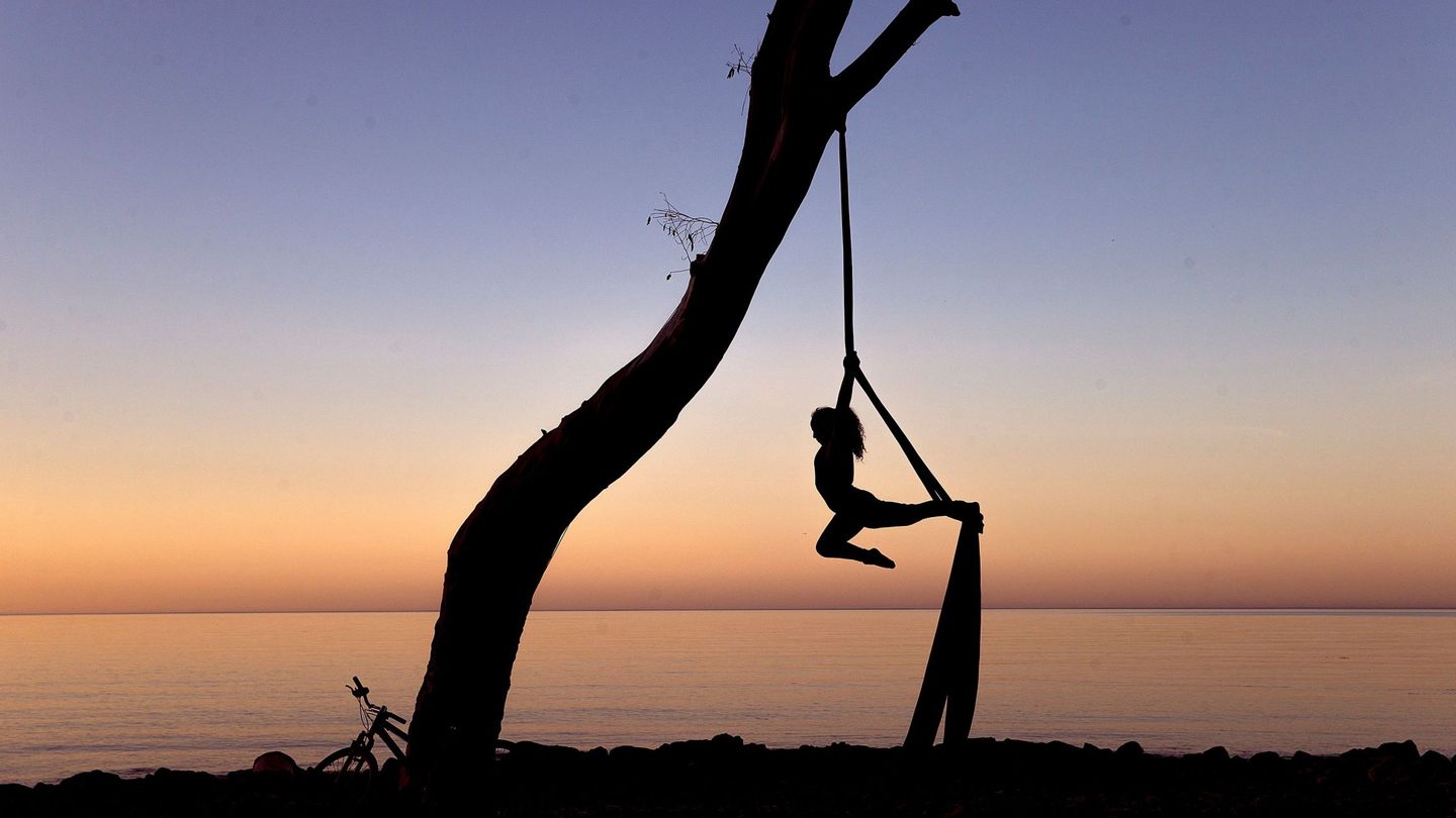 Una mujer realiza acrobacias al amanecer en los Baños del Carmen. (EFE/Jorge Zapata)