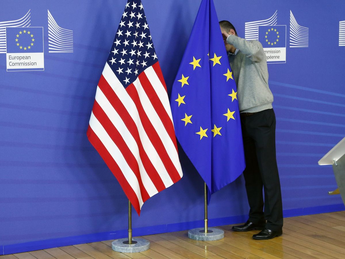 Foto: Un trabajador de la Comisión Europea sitúa la bandera americana y europea. (Reuters)