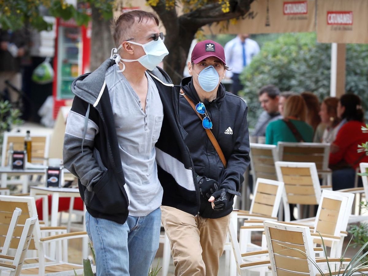 Foto: Dos personas con mascarillas caminan junto a la terraza de un bar en Sevilla, en una imagen de archivo. (EFE/José Manuel Vidal)