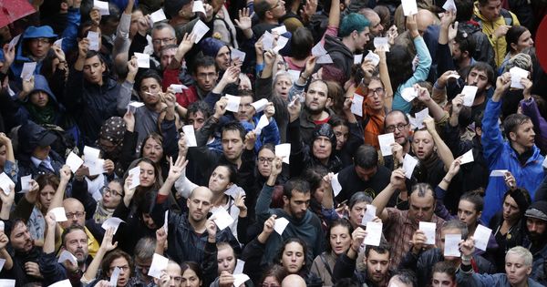 Foto: Un grupo de personas muestran papeletas en los alrededores del colegio Ramón Llull de Barcelona durante el referédum (EFE)