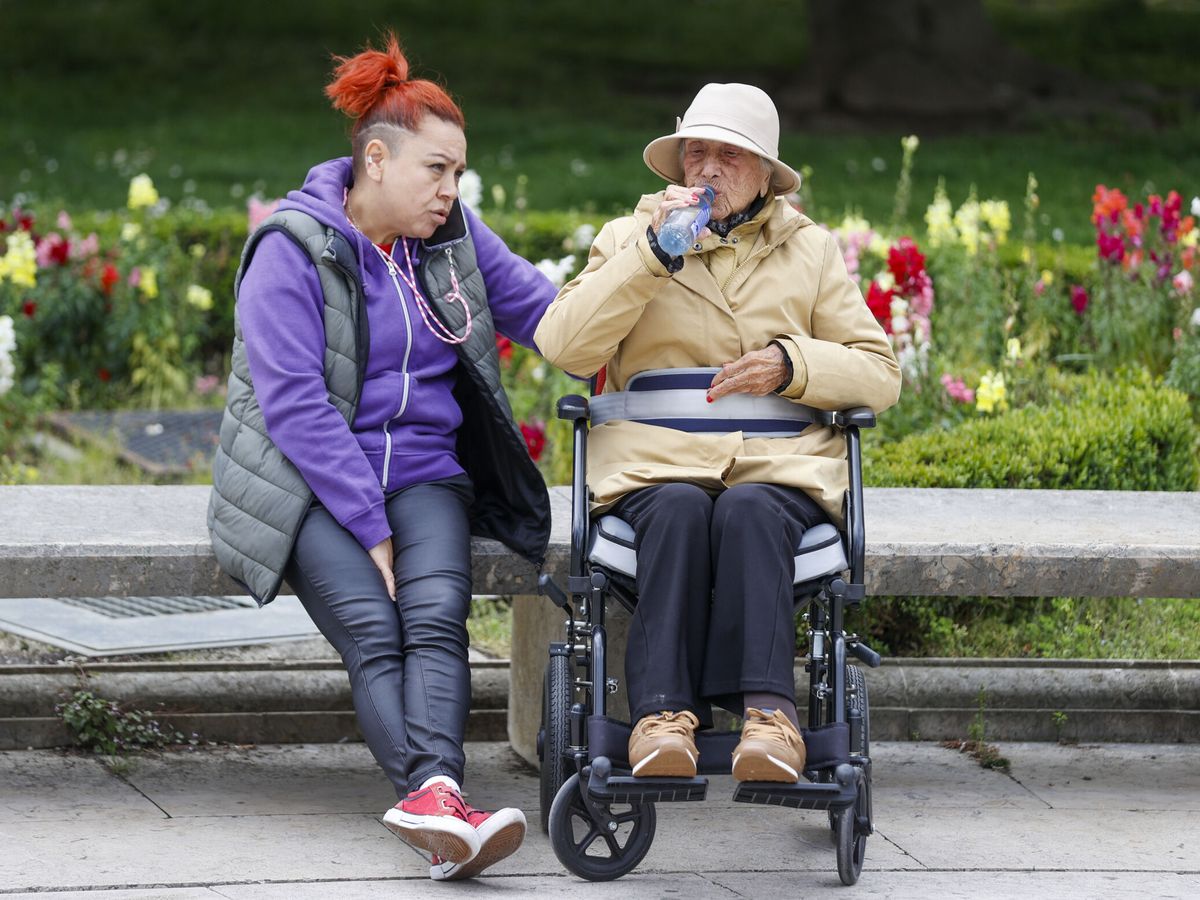 Foto: Una mujer dependiente, junto a su cuidadora, en un parque. (EFE/Luis Tejido)