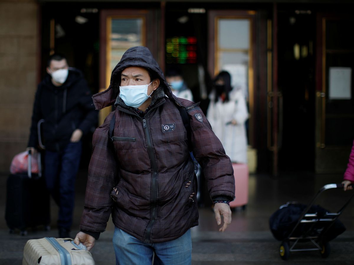 Foto: Un viajero porta su maleta ataviado con una mascarilla. (Reuters)