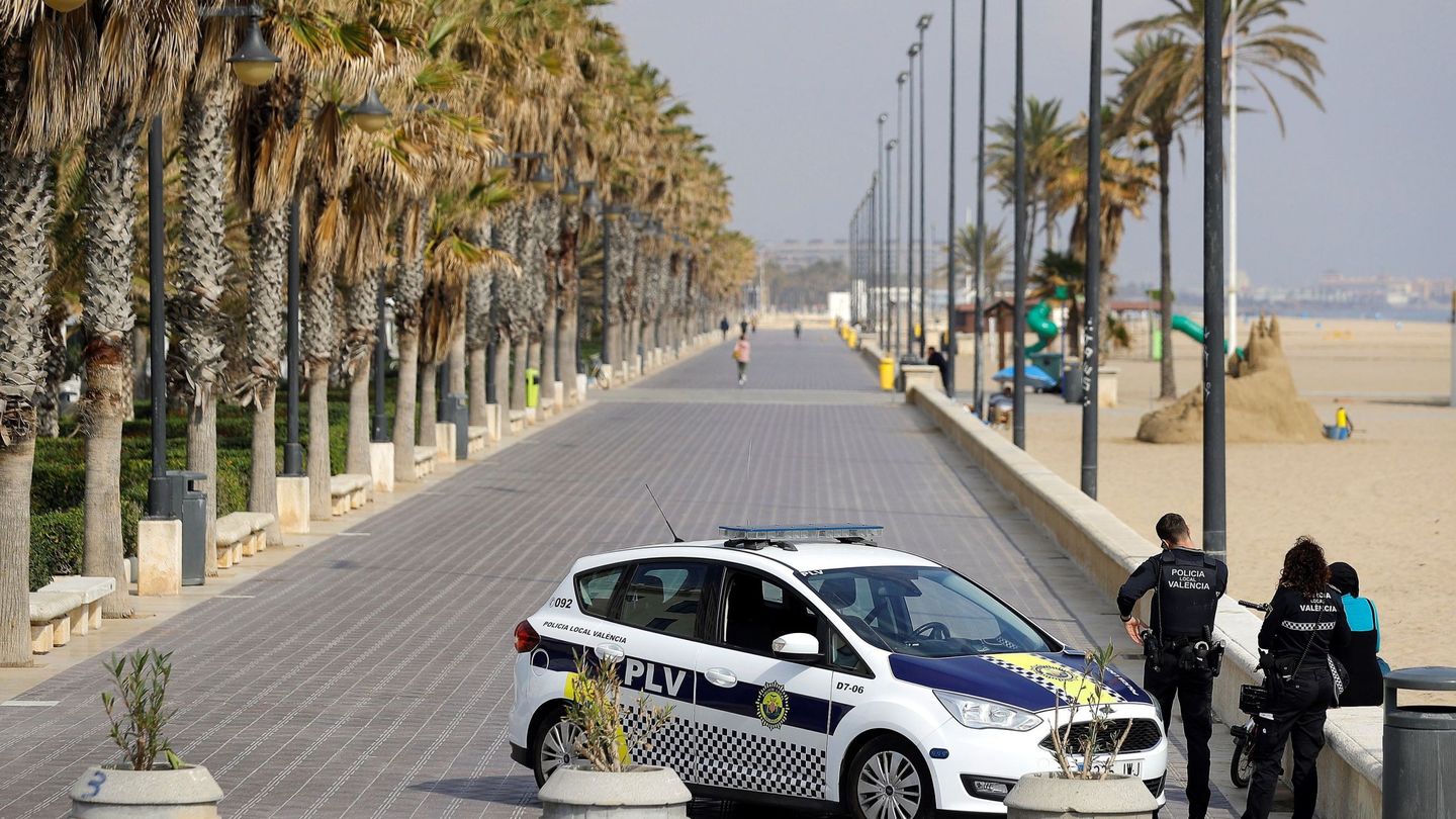 Un coche de la Policía Local de Valencia patrulla el paseo marítimo, conminando las personas a que regresen a casa. (EFE)
