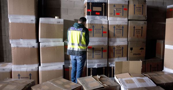 Foto: Un policía inspecciona bienes de afectados por la estafa de una empresa de paquetería. (EFE)