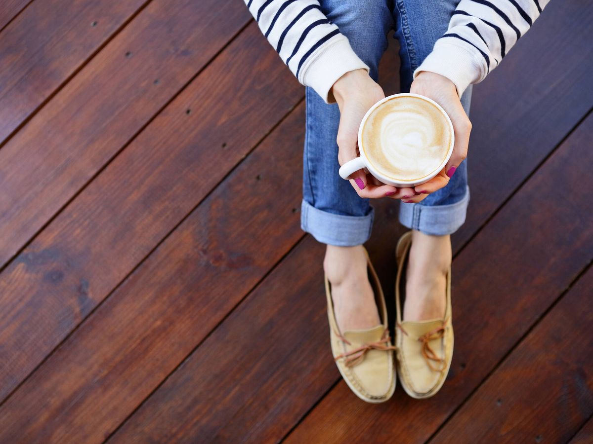 Foto: Una mujer luce sus zapatos con una taza de café. (iStock)