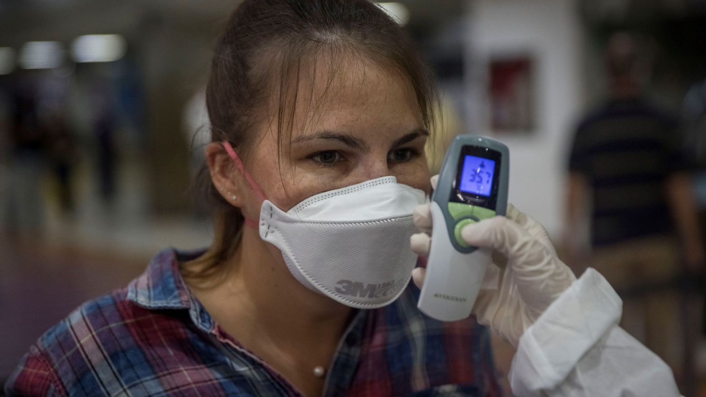 Un trabajador sanitario toma la temperatura de ciudadanos europeos en el Aeropuerto Internacional Simón Bolívar de Maiquetía, en La Guaira, Caracas (Venezuela). (EFE)