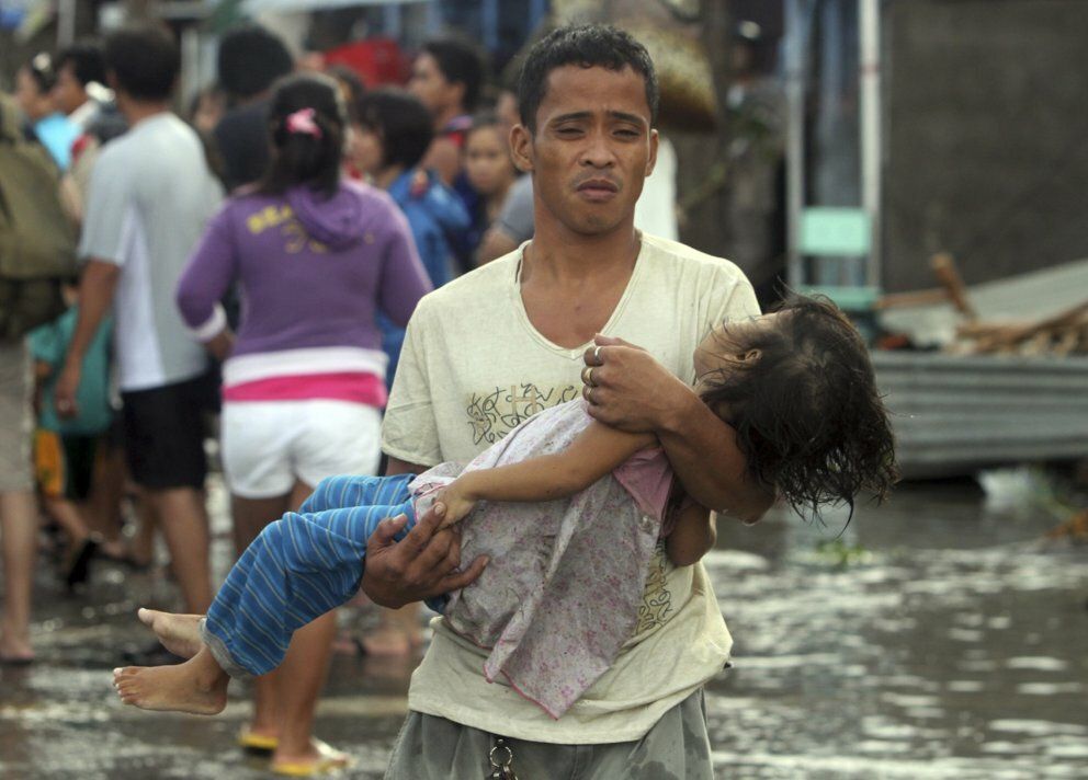 A father carries the lifeless body of his daughter on the way to the morgue after super typhoon haiyan hit tacloban