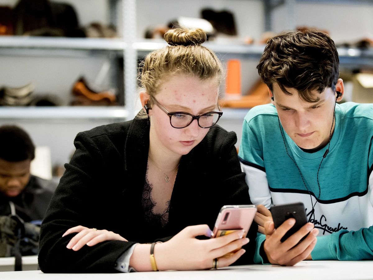 Foto: Dos jóvenes utilizan sus teléfonos móviles. (EFE)