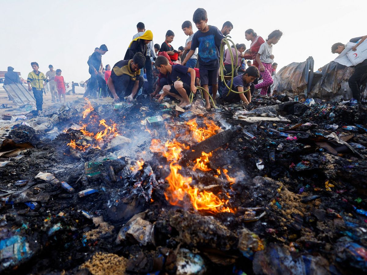 Foto: Niños palestinos buscan comida entre escombros quemados tras un ataque israelí contra una zona designada para personas desplazadas, en Rafah (Reuters/Mohammed Salem)