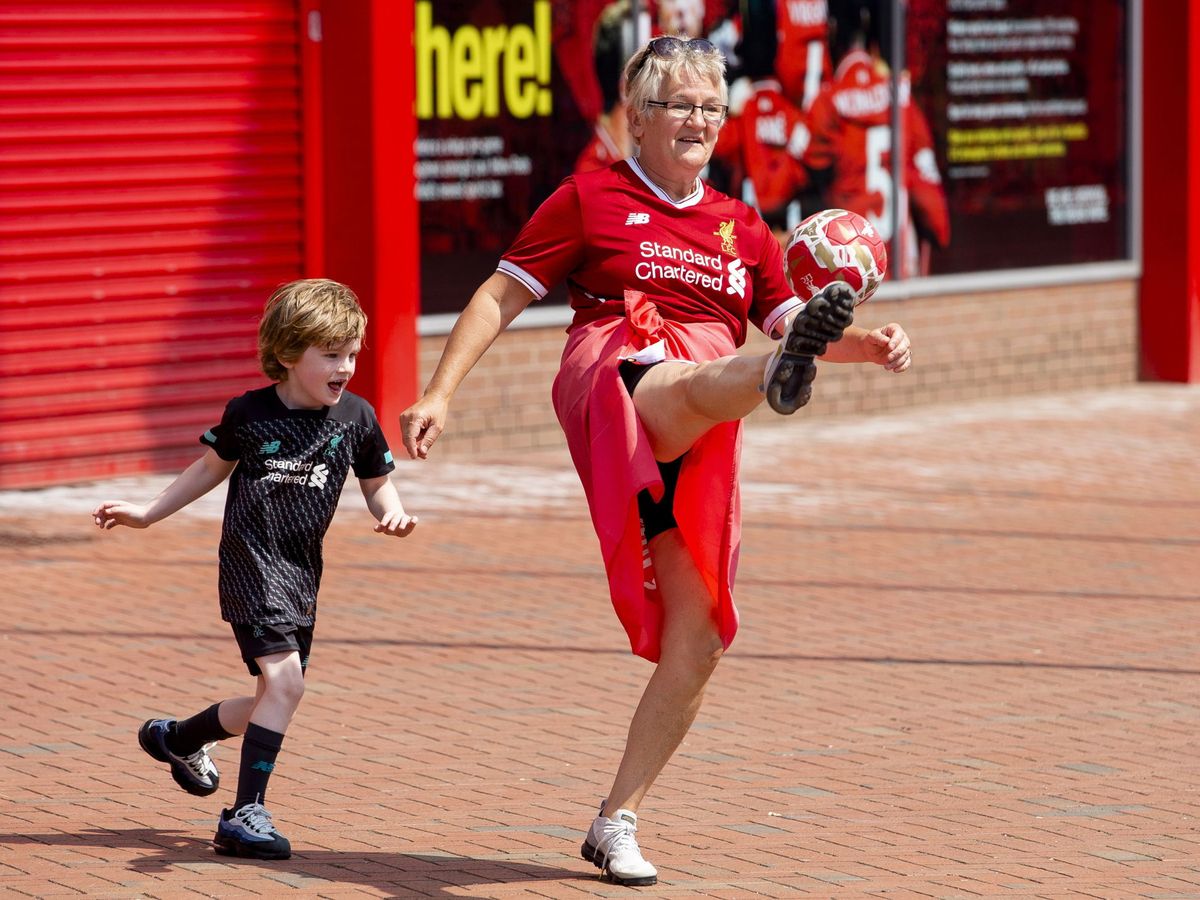 Foto: Una mujer celebra con su nieto el título del Liverpool en los aledaños de Anfield. (Reuters)