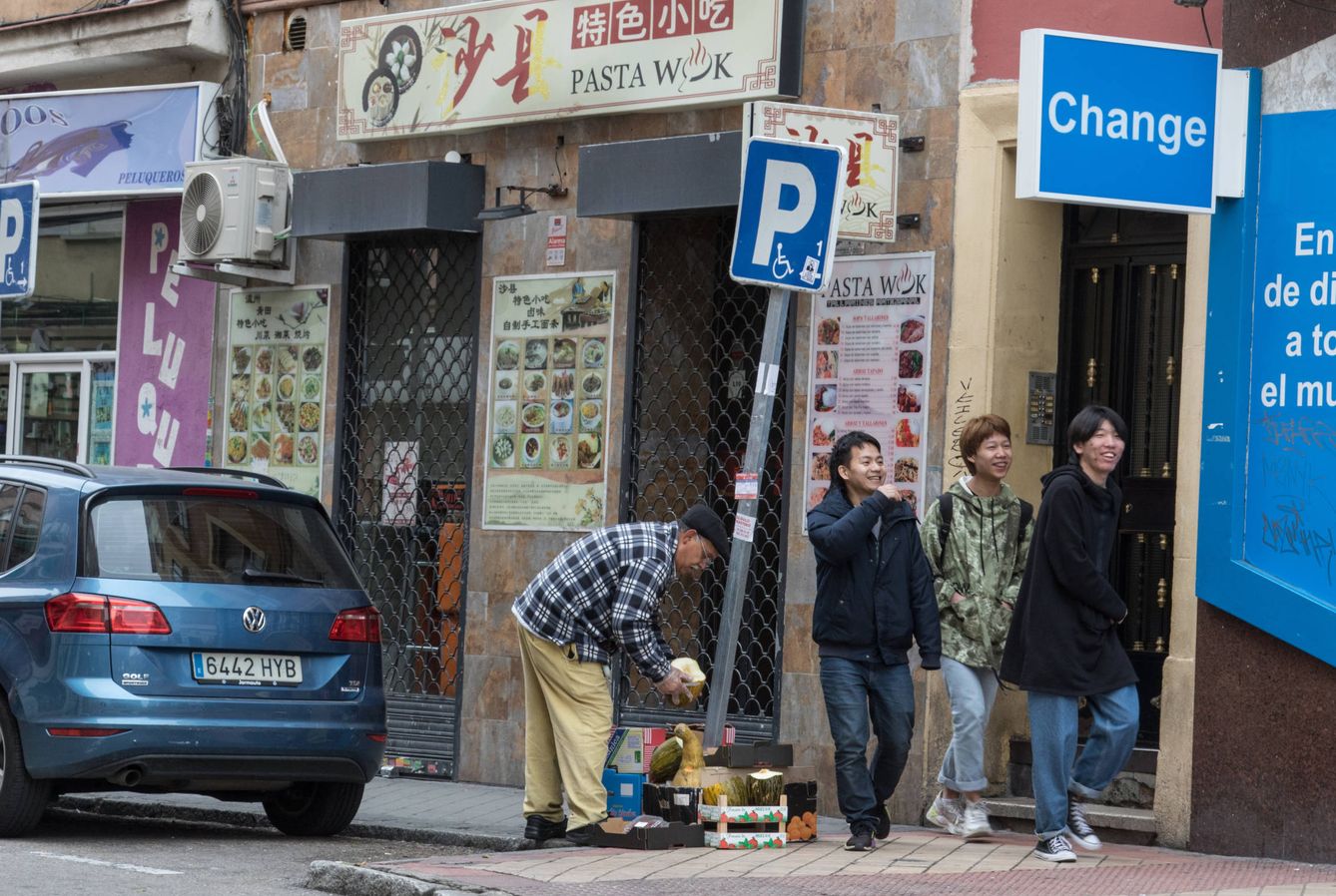 Tres jóvenes pasan de largo por un restaurante cerrado en Usera, Madrid. (D. B.)