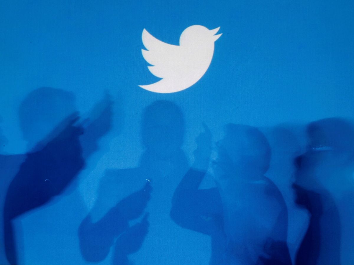 Foto: Sombras de personas sujetando móviles con el logo de Twitter de fondo. (Reuters/Kacper Pempel)
