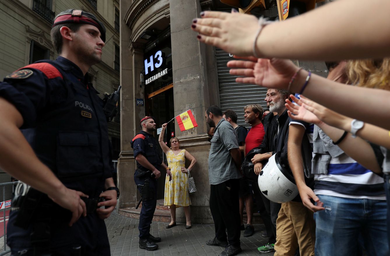 Una mujer agita una bandera española frente a un 'mosso'. (Reuters)