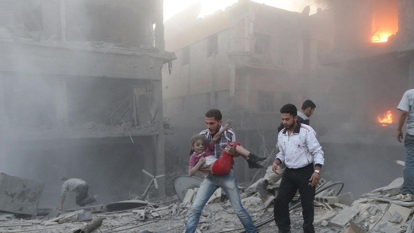 Un hombre rescata a una niña superviviente de un ataque aéreo del régimen de Asad en Douma, Damasco, en junio de 2015. (Reuters)