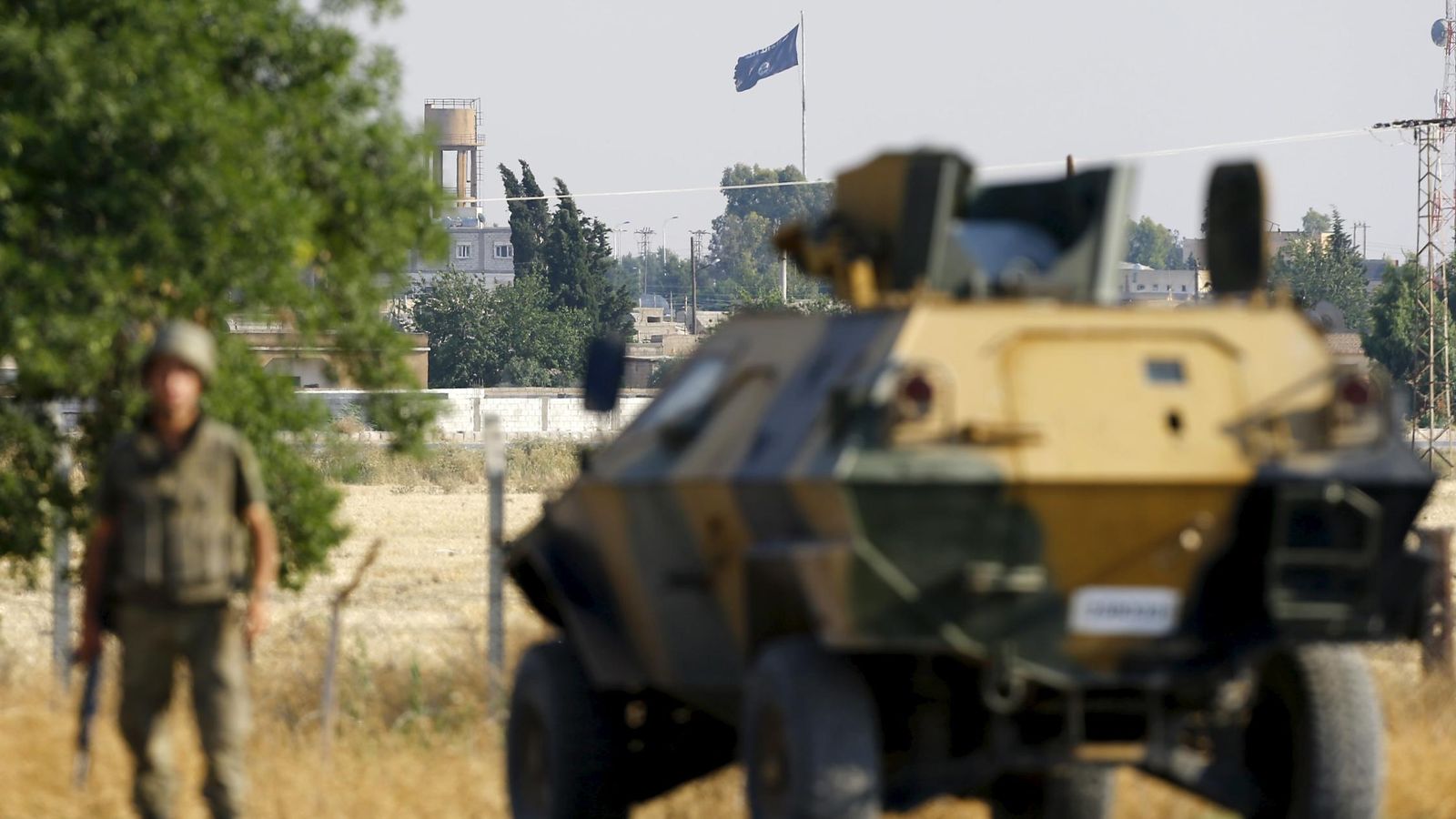 Foto: Un blindado turco custodia el paso fronterizo entre Akçakale (Turquía) y Tel Abyad (Siria). Al fondo ondea una bandera del Estado Islámico (Reuters)