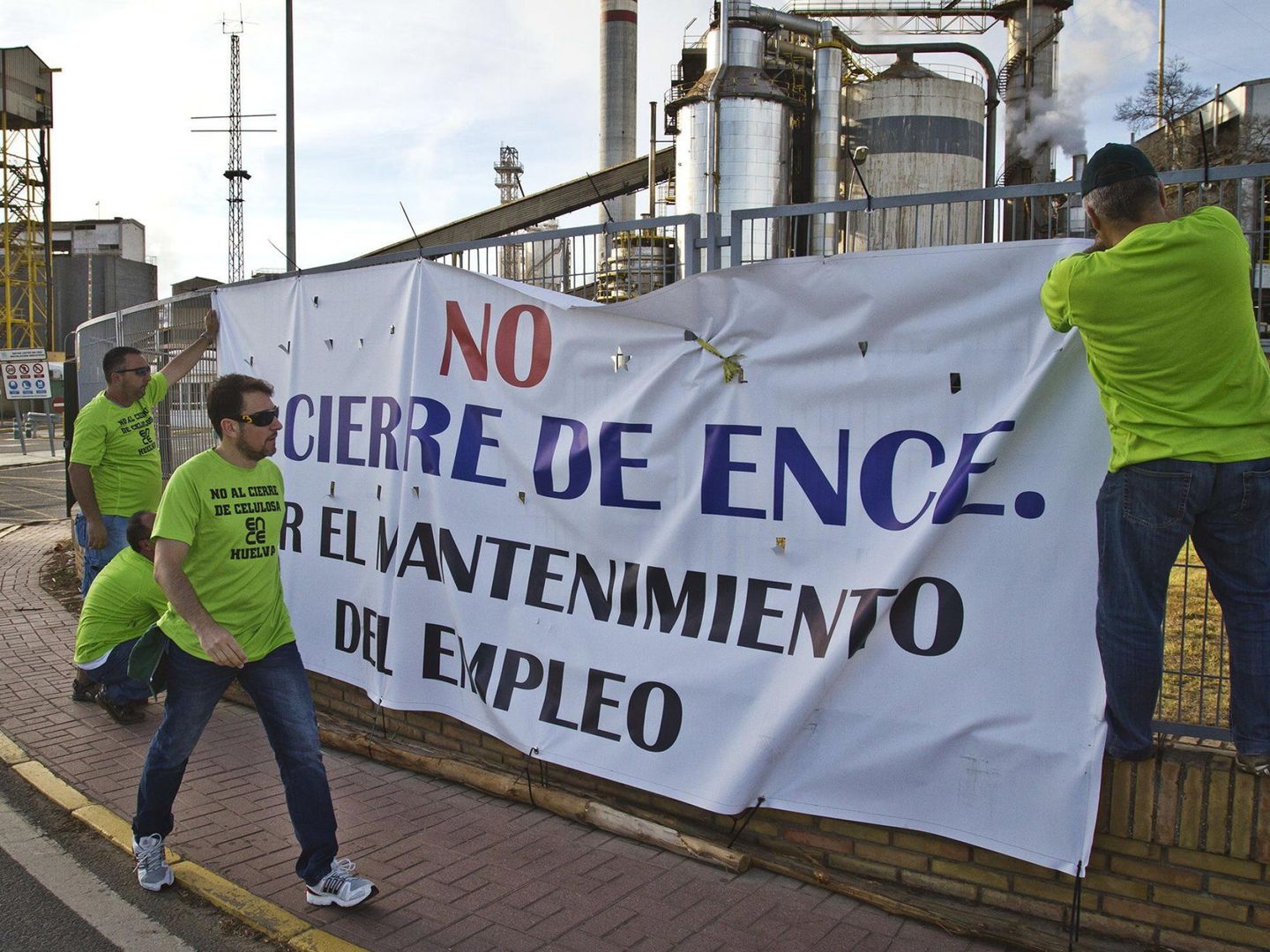 Trabajadores de Ence colocan una pancarta tras el anuncio de la empresa del cierre. (EFE)