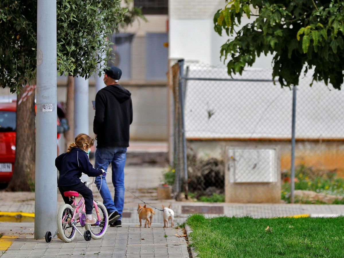 Foto: Un padre junto a su hija pasea a sus dos perros en una calle de Valencia el pasado 17 de abril. (EFE)