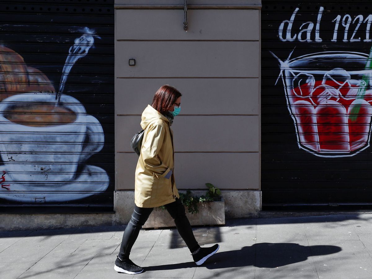 Foto: Una mujer con mascarilla frente a un bar cerrado (Reuters)