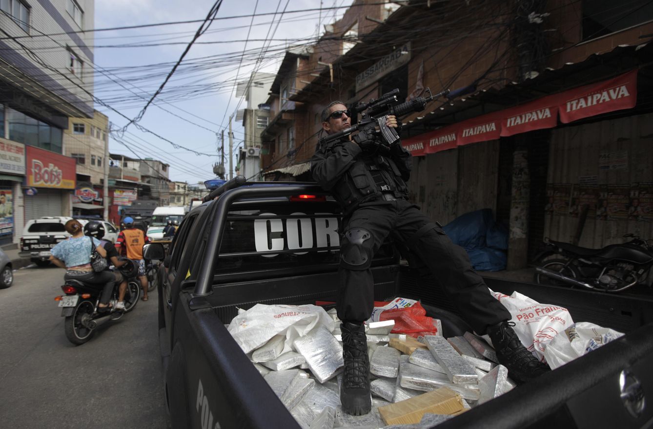 Foto: Un agente de policía apunta con su arma sentado sobre paquetes de marihuana confiscados durante una operación en la favela de Rocinha, en Río (Reuters).