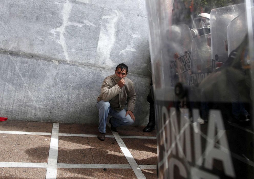 Foto: Un manifestante en una protesta contra las medidas de austeridad se protege del gas lacrimógeno en Atenas. (Reuters)