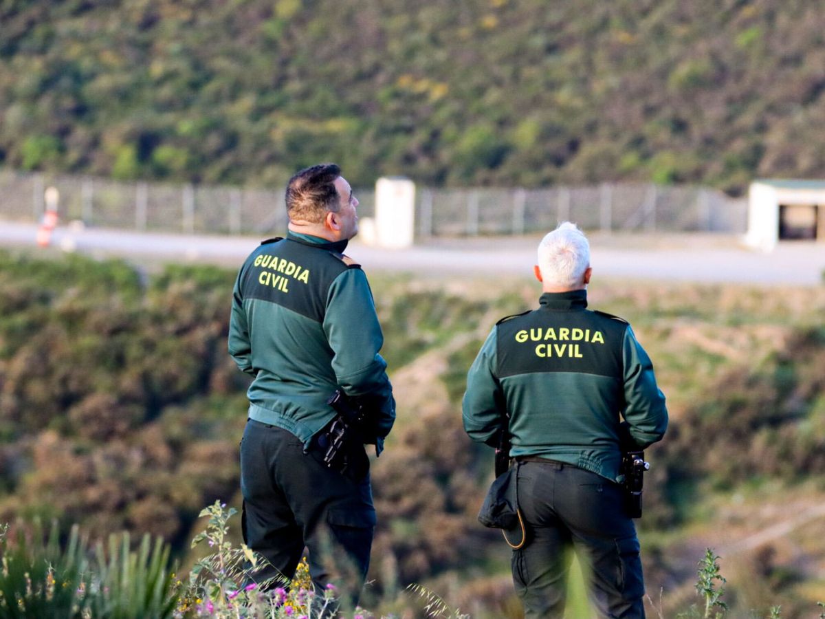 Foto: Dos agentes de la Guardia Civil vigilan desde un monte junto a la zona fronteriza en Ceuta. (EFE/Reduan Dris)
