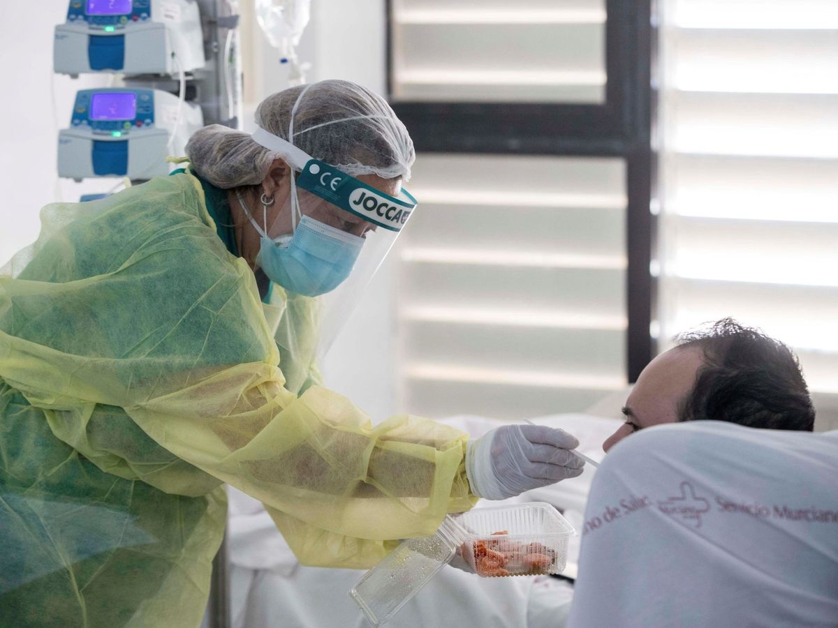 Foto: Una trabajadora sanitaria ayuda a comer a un paciente de coronavirus ingresado en UCI (EFE)