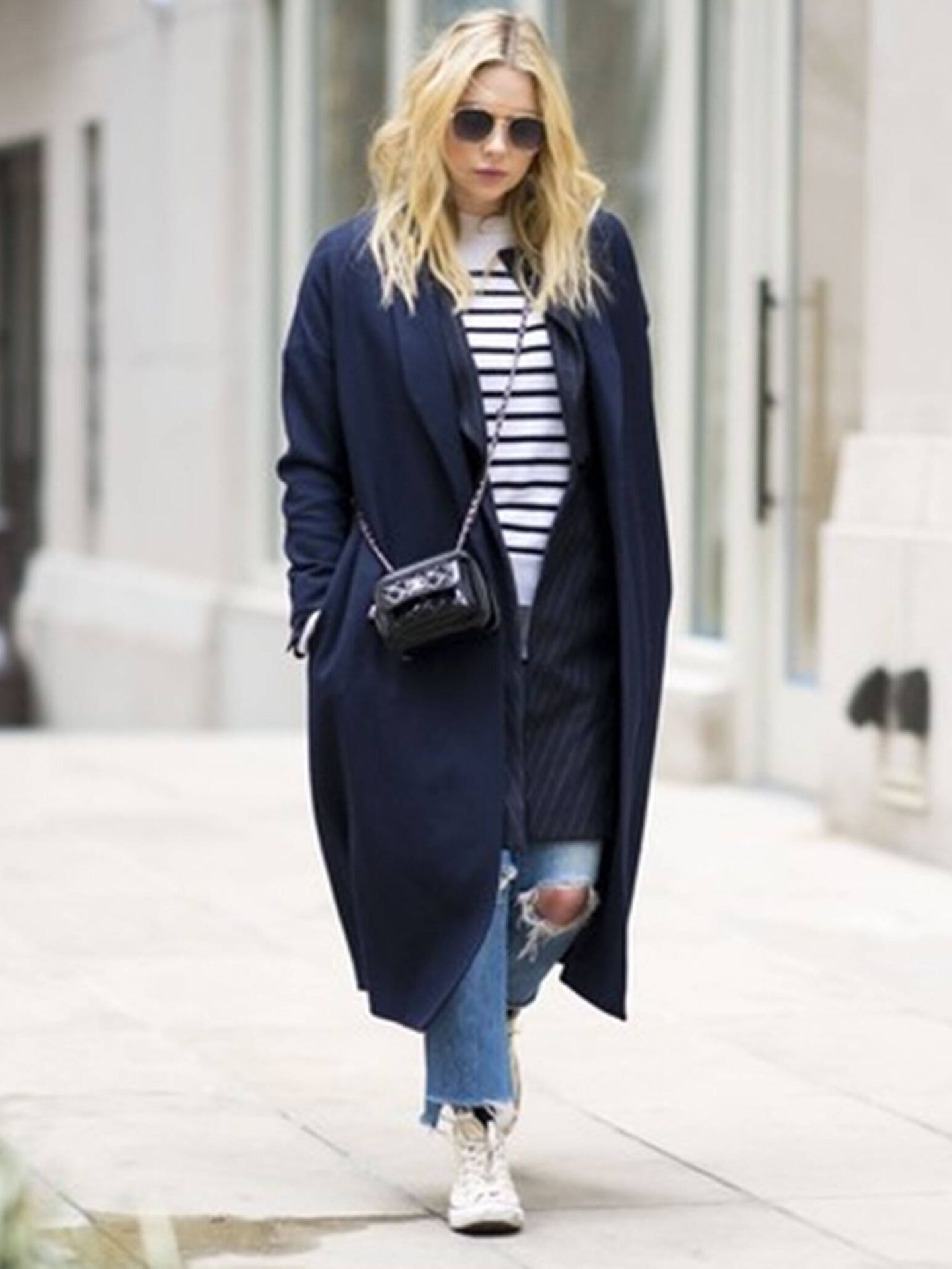 Una 'it girl' luce el abrigo azul marino con camiseta de rayas estilo marinera y vaqueros. (Imaxtree)