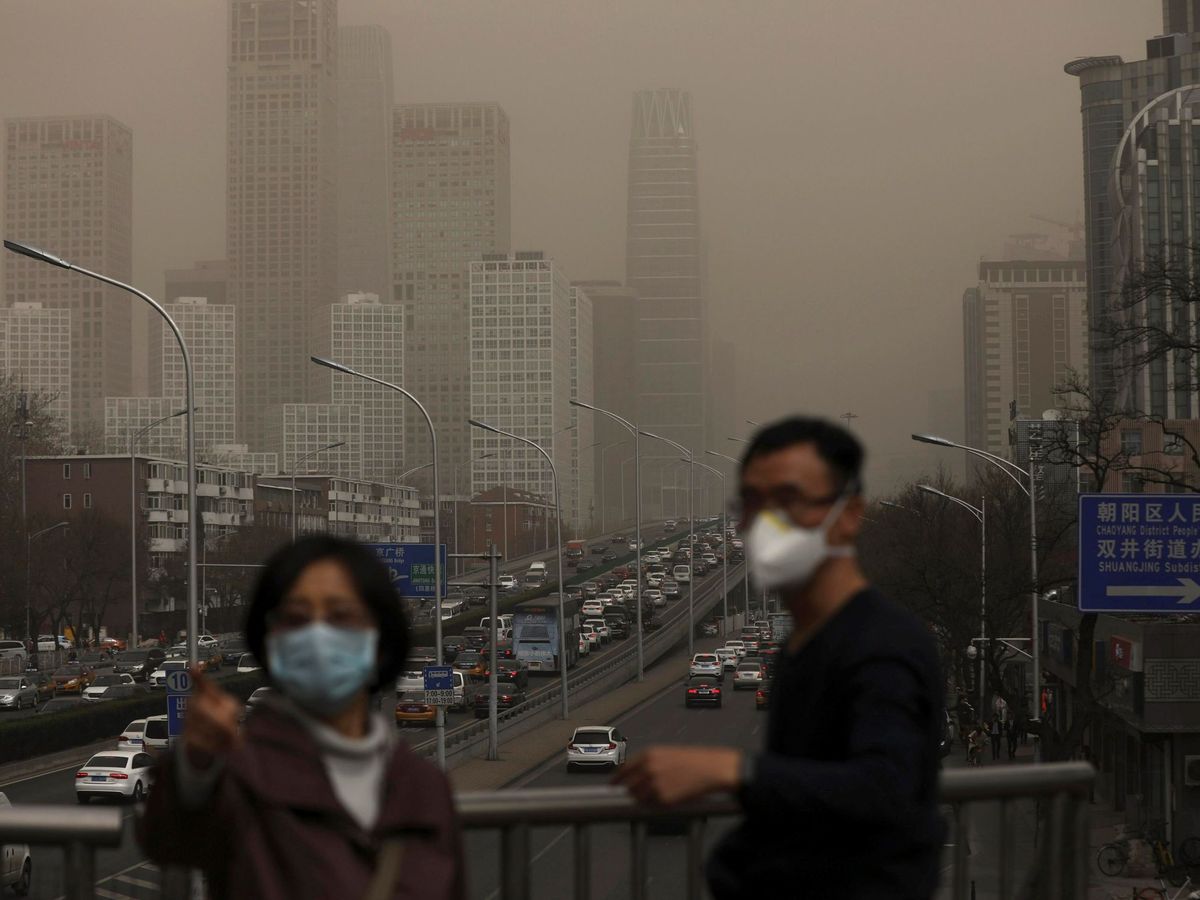 Foto: n hombre y una mujer se protegen con máscaras de la nube de contaminación que cubre la ciudad de Pekín (China). (EFE)