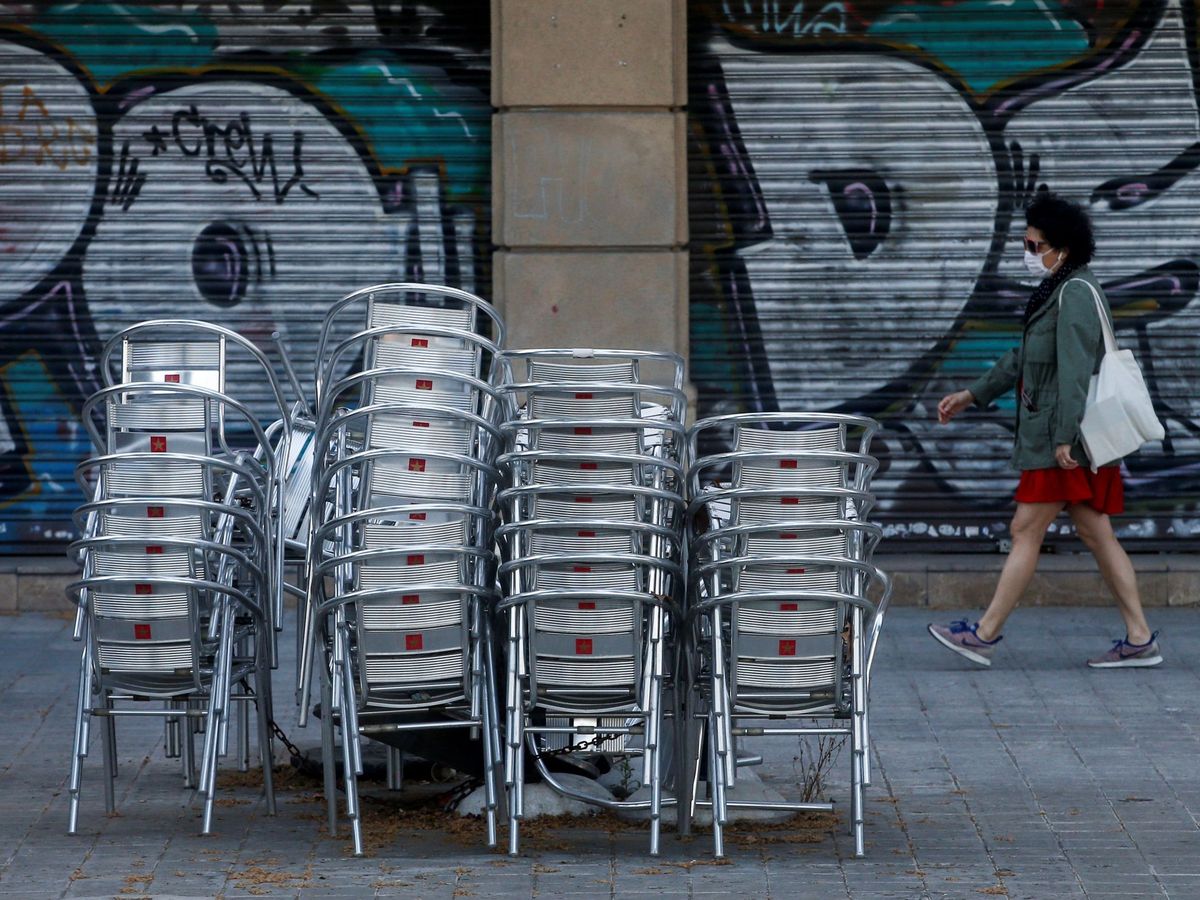 Foto: Una mujer pasa con mascarilla delante de un restaurante cerrado en la Rambla de Cataluña, en Barcelona, este 18 de mayo. (EFE)