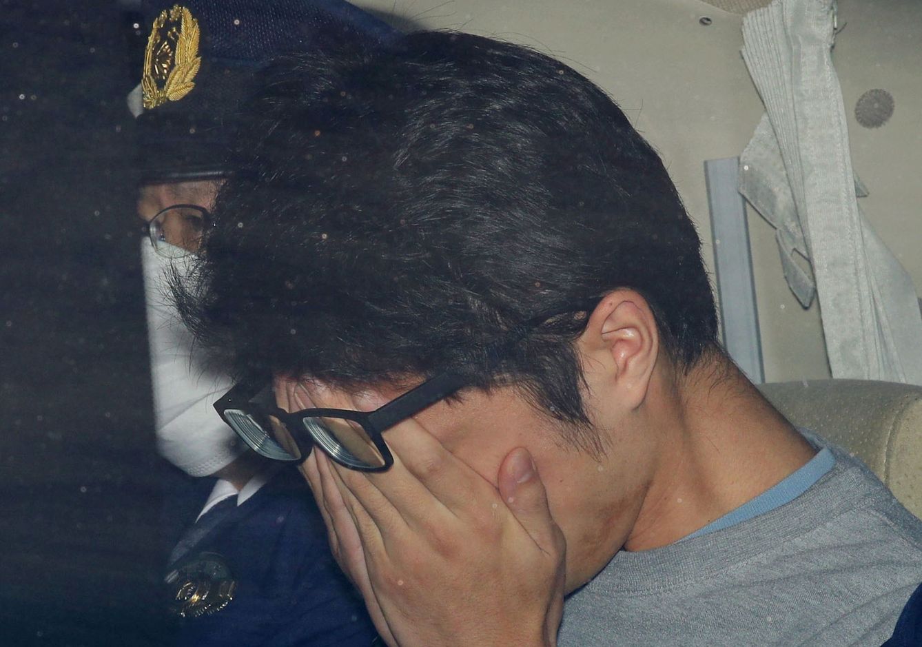 Shiraishi Takahiro se tapa la cara tras ser detenido. (Reuters)
