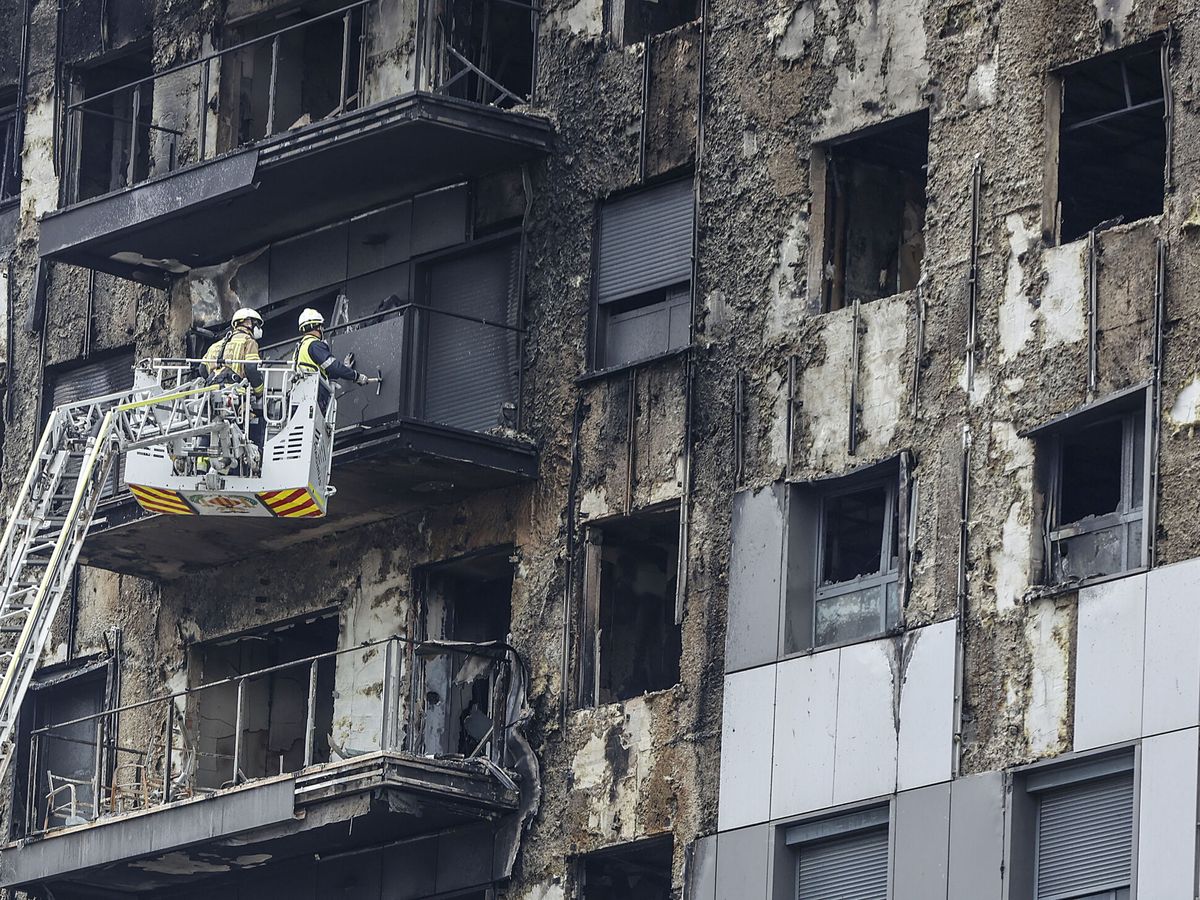 Foto: Bomberos en una grúa sanean la fachada quemada del edificio que ardió en Valencia. (Rober Solsona / Europa Press)