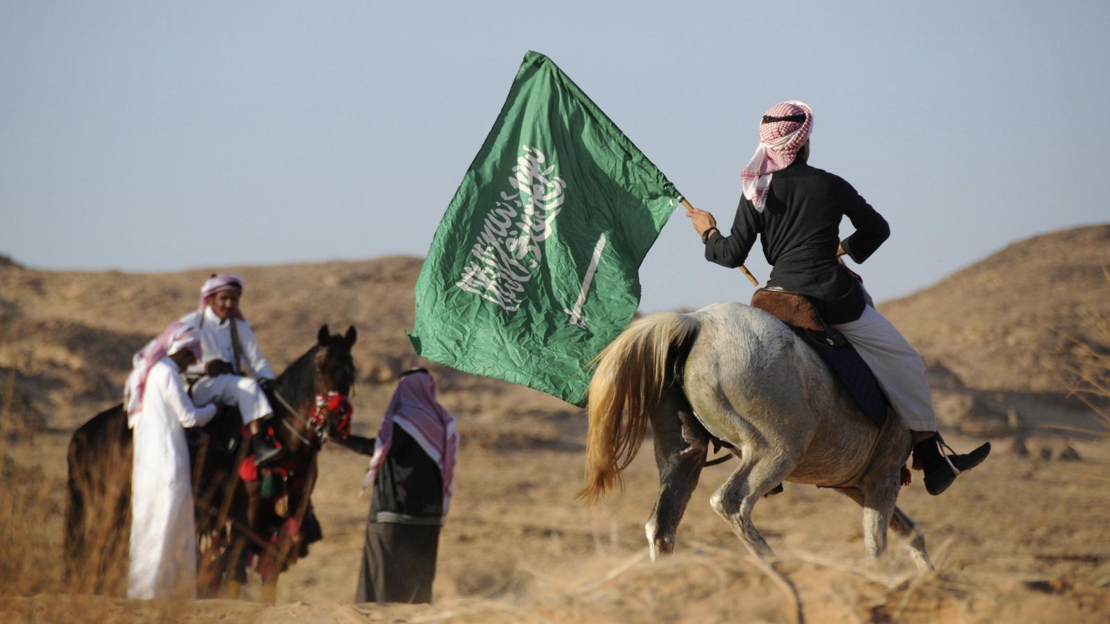 Foto: Un hombre a caballo ondea la bandera nacional de Arabia Saudita. (Reuters)