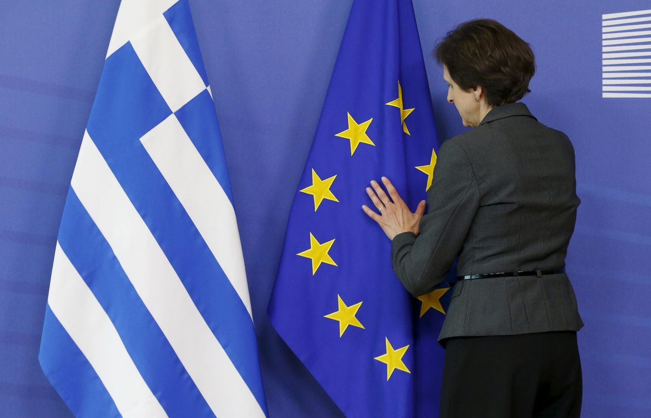 Una trabajadora arregla las banderas de Grecia y la UE. (EFE)