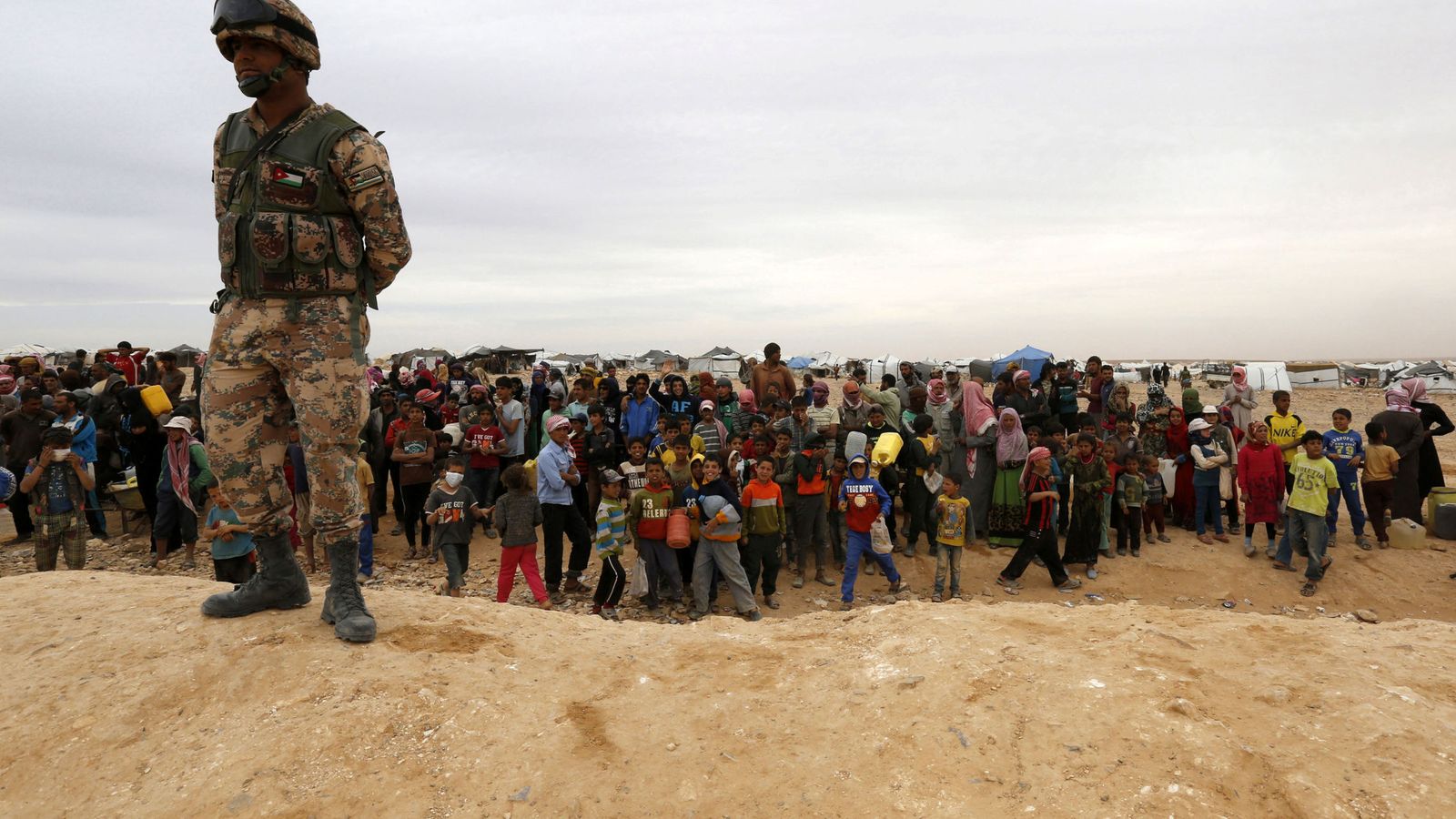 Foto: Un soldado jordano monta guardia frente a un grupo de refugiados sirios atrapados en la frontera, cerca de Ruwaished (Reuters)