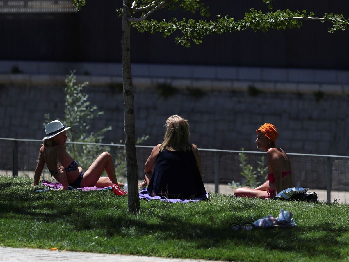 Foto: Tres mujeres toman el sol en los jardines de Madrid Rio. (Efe)