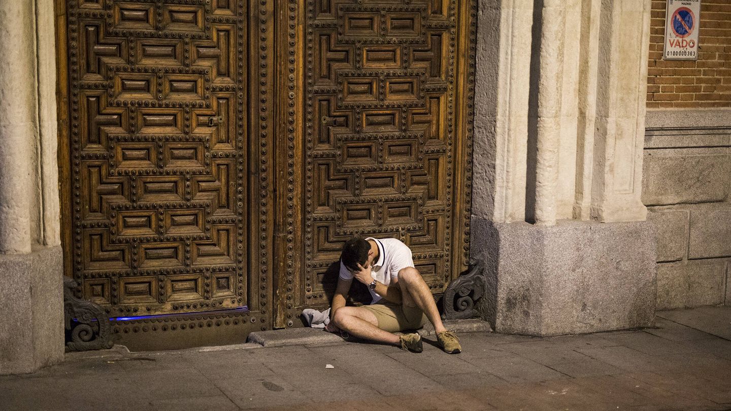 Un chico descansa en una puerta del centro de Madrid. (A. M.)
