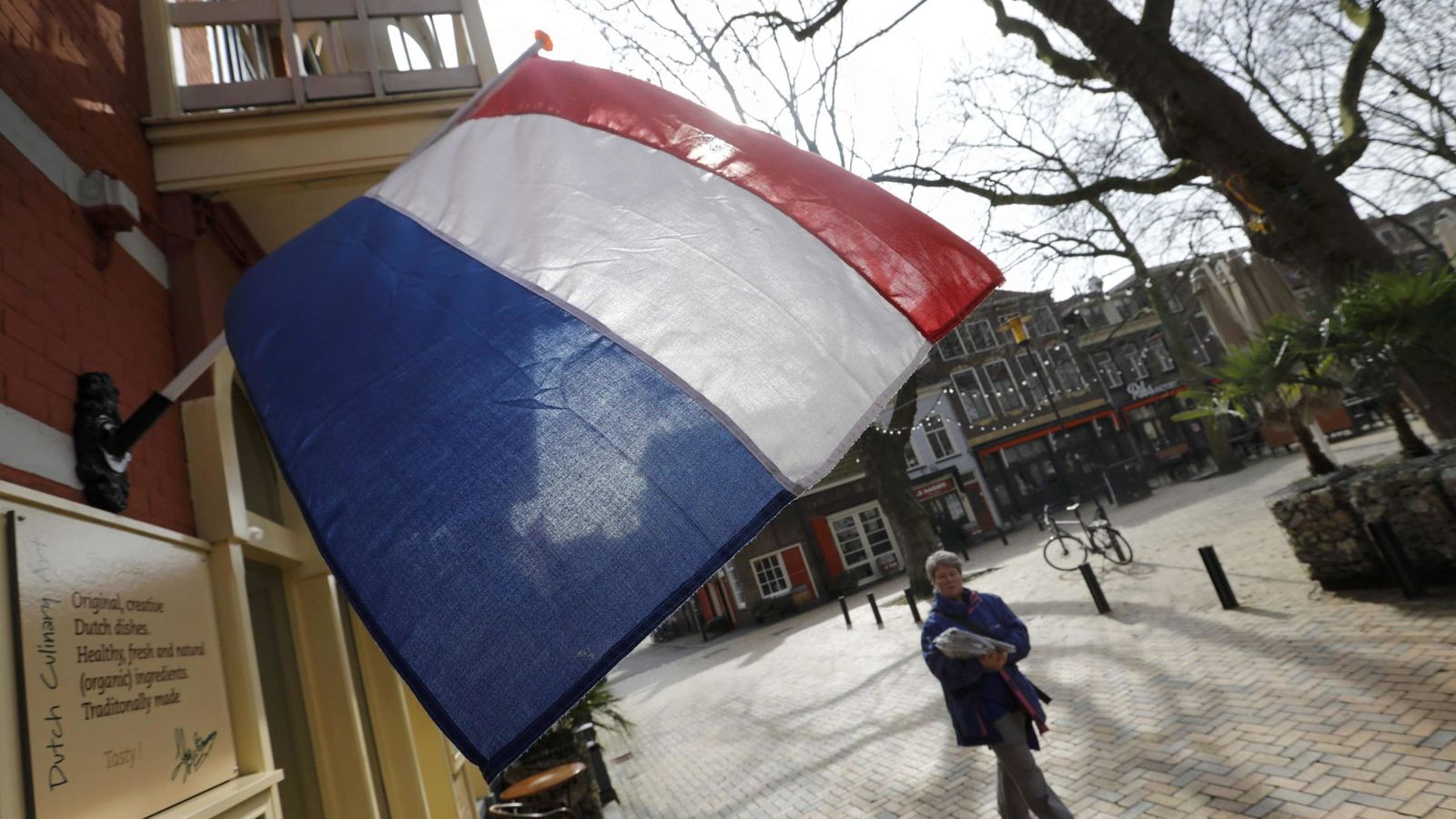 Foto: Una mujer pasa por debajo de una bandera holandesa el día antes de las elecciones en Delft, el 14 de marzo de 2017. (Reuters)