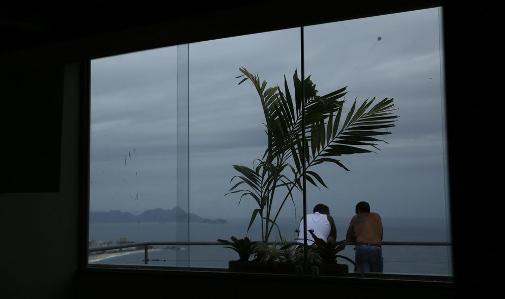 Obreros observan la playa de Ipanema desde un hotel en construcción en Río (Reuters).