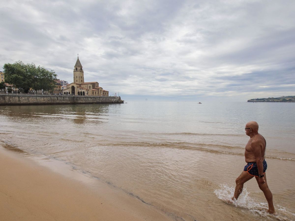 Foto: Un hombre sale del agua en Gijón, ciudad señalada por su nula depuración de residuos. (EFE)
