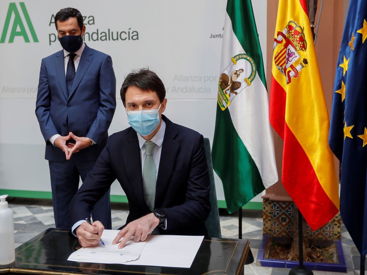 Foto: Juan López-Belmonte hijo firma un documento ante Juanma Moreno. (EFE)