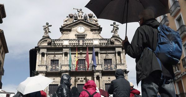 Foto: Un grupo de turistas se protege con sus paraguas de la lluvia junto al Ayuntamiento de Pamplona a finales de marzo. (EFE)