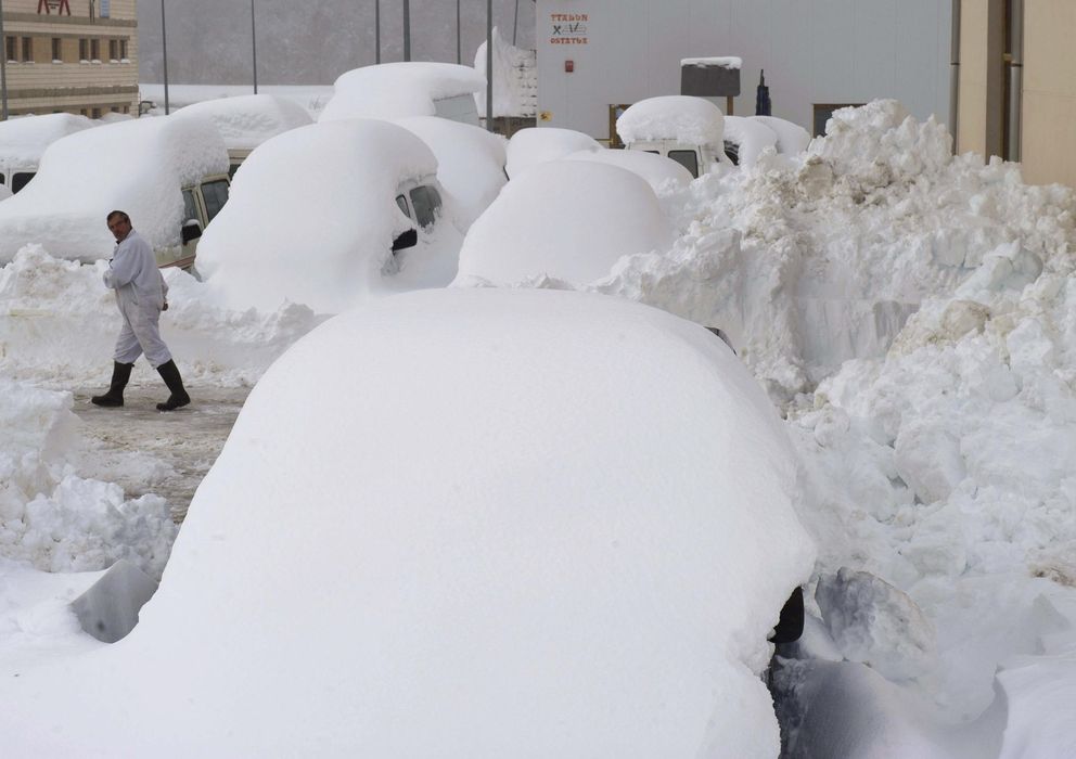 Foto:  Una persona camina entre los coches cubiertos de nieve en Burguete (Navarra) (EFE)