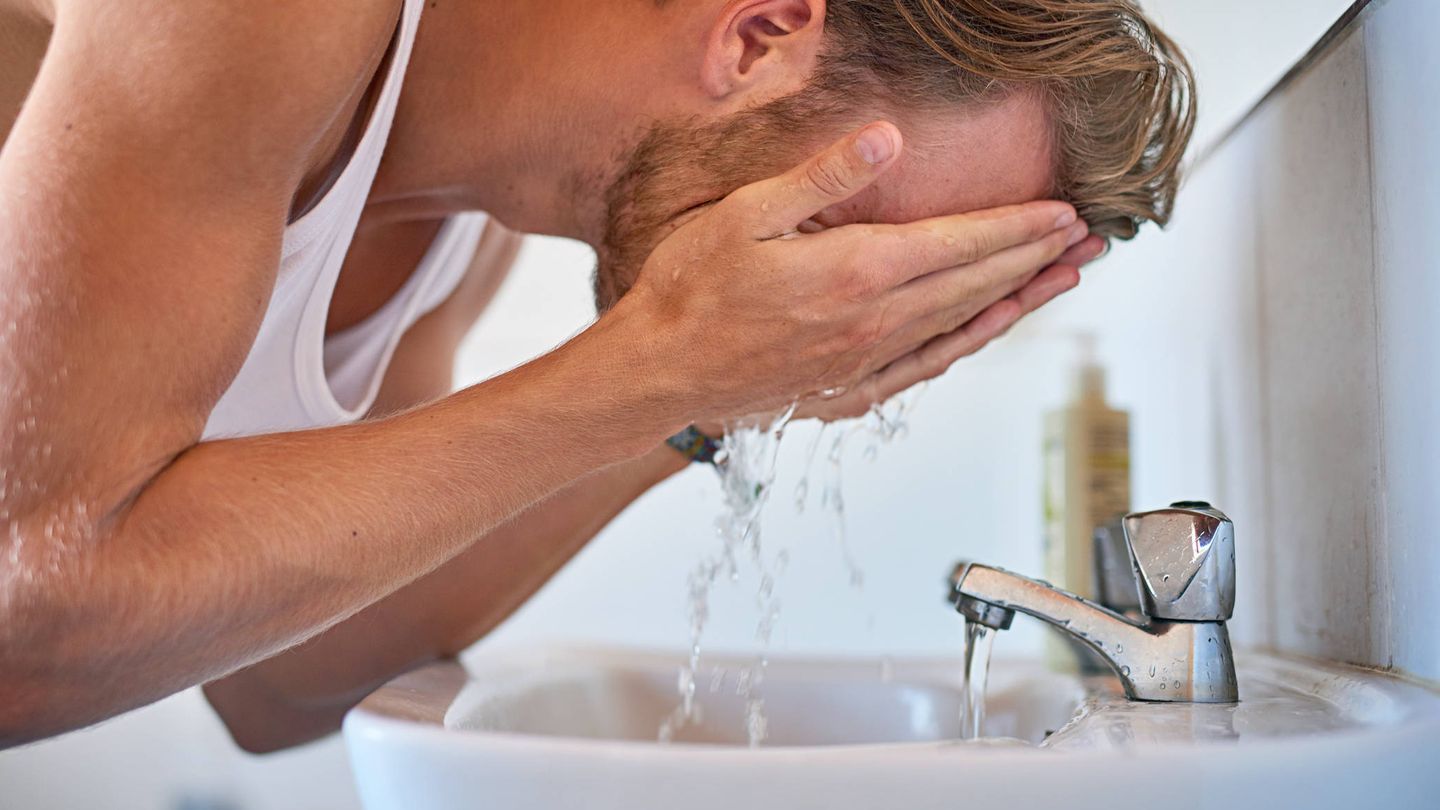 Un hombre se lava la cara en el lavabo. (iStock)