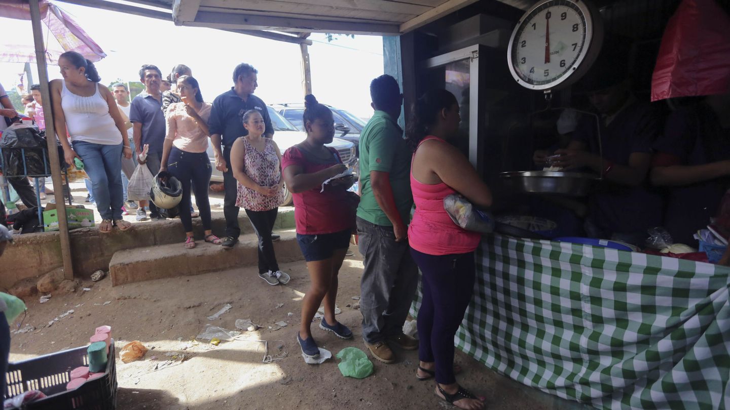 Ciudadanos hondureños guardan una fila para comprar alimentos en un feria de agricultores. (EFE)